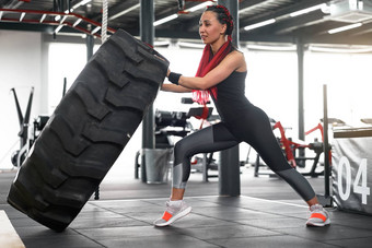 运动员运动型女人电梯轮健身房交叉培训推大轮胎中间成人英俊的运动员健美运动员举重运动员理想的身体