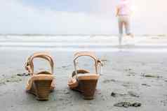 海滩假期旅行假期生活方式概念快乐中间岁的业务女人鞋运行海光着脚享受美丽的海滩