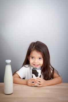 可爱的婴儿女孩持有玻璃牛奶喝牛奶