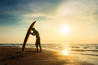 冲浪水体育运动户外活动生活方式概念轮廓年轻的快乐冲浪男人。白色海滩冲浪板冲浪者海滩海海岸日落时间美丽的光