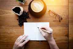 咖啡师咖啡馆使咖啡准备服务男人。持有笔写作请注意空白色页面空间文本古董办公室桌子上装饰卡布奇诺咖啡咖啡咖啡豆前视图