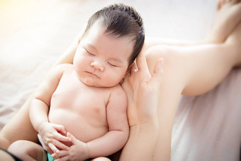 概念爱家庭的关系关闭新生儿可爱的亚洲婴儿眼睛关闭感觉舒适的睡觉手年轻的妈妈。首页前视图亚洲婴儿肖像