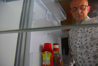 饿了男人。开放食物冰箱空冰箱高级男人。零食冰箱晚上视图冰箱