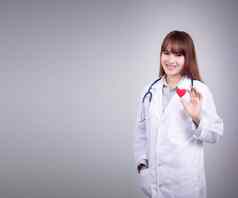 年轻的亚洲医生站持有红色的心手笑脸脸衣服医生礼服统一的听诊器医院美丽的亚洲女模型