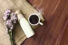 热黑暗咖啡烟新鲜的牛奶瓶袋背景木表格装饰美丽的花花束前视图