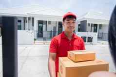 亚洲交付军人穿红色的统一的红色的帽处理纸板盒子给女客户前面房子在线购物表达交付