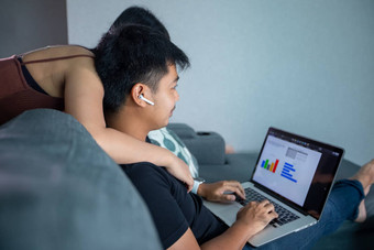亚洲年轻的微笑夫妇拥抱无线耳机电脑笔记本工作首页准备图信息在线会议首页