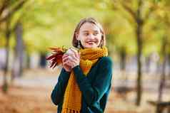 快乐年轻的女孩黄色的围巾走秋天公园