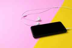 智能手机耳机听古董音乐黄色的粉红色的背景