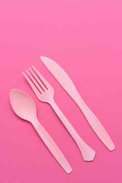 平躺粉红色的塑料餐具粉红色的背景