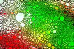 色彩斑斓的滴石油水黄色的红色的绿色彩色的圈椭圆摘要背景设计