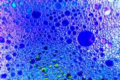 色彩斑斓的滴石油水蓝色的紫色的彩色的圈椭圆摘要背景设计