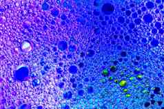 色彩斑斓的滴石油水蓝色的紫罗兰色的彩色的圈椭圆摘要背景设计
