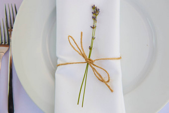 优雅的表格设置婚礼订婚复活节晚餐白色陶瓷盘子棉花餐巾系线薰衣草花蜡烛普罗旺斯风格