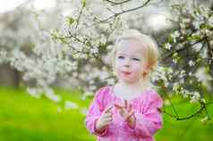 可爱的蹒跚学步的女孩盛开的樱桃花园