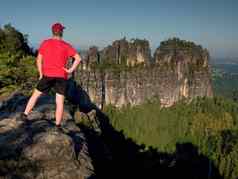 成人徒步旅行者红色的衬衫黑暗裤子男人。砂岩悬崖