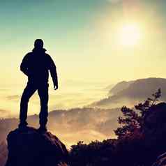 徒步旅行者爬上峰岩石谷男人。看有雾的多雾的早....谷