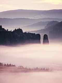 梦幻有雾的森林景观雄伟的山峰岩石减少照明雾深谷