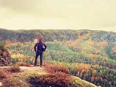 徒步旅行者运动服装站岩石看秋天的色彩斑斓的谷太阳