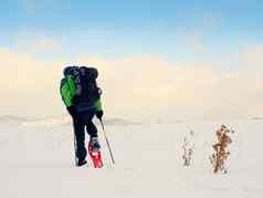 男人。清洁雪鞋徒步旅行者绿色灰色的冬天夹克黑色的徒步旅行裤子走雪提起
