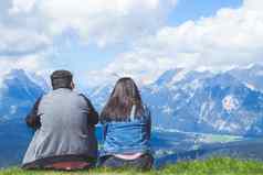 夫妇旅行者坐着欣赏风景阿尔卑斯山脉山