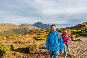 年轻的徒步旅行夫妇走路特本跟踪阳光明媚的一天徒步旅行者携带背包踩关键峰会跟踪假期峡湾国家公园新西兰