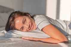 快乐首页放松亚洲微笑女人住床上放松卧室坦诚的肖像自然美健康的护肤品模型脸舒适的泡沫床垫枕头