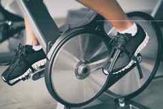 健身机首页女人骑自行车室内静止的自行车锻炼在室内有氧运动锻炼特写镜头鞋子自行车