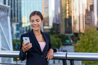女人短信发短信应用程序聪明的电话城市业务区年轻的业务女人智能手机微笑快乐穿西装夹克在户外城市女专业