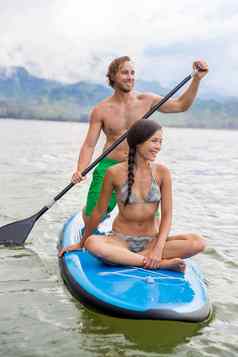 paddleboard夫妇有趣的paddleboarding夏威夷海滩假期夏天假期女人坐着董事会男人。桨