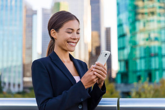 女人短信发短信应用程序聪明的电话城市业务区年轻的业务女人智能手机微笑穿西装夹克城市背景市中心温哥华加拿大
