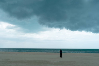 男人。站海滩黑暗巨大的云天空黑色的狂风暴雨的云运动大雨一天