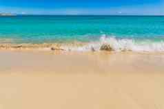 绿松石蓝色的海水波沙子海滩阳光明媚的蓝色的天空