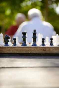 活跃的退休人朋友玩国际象棋公园