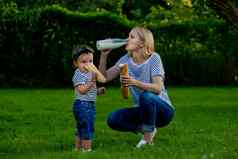 年轻的女人牛仔裤条纹t恤喝牛奶玻璃瓶家庭野餐