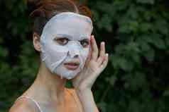 美丽的女人白色面具手脸复制空间美容灌木背景