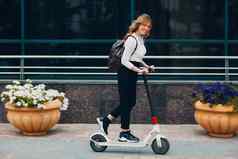 年轻的女人开车电踏板车城市