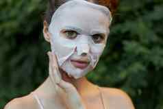肖像女孩化妆品面具触摸脸手清晰的皮肤