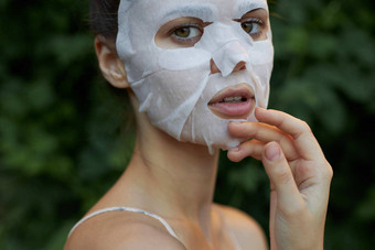 美丽的女人抗皱面具触摸脸手皮肤护理叶子背景