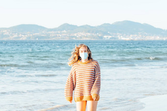 年轻的女人海滩外科手术面具明亮的一天穿毛衣复制空间快乐资质