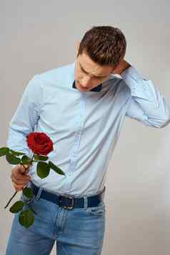 英俊的男人。红色的玫瑰蓝色的衬衫弓领带光背景裁剪视图