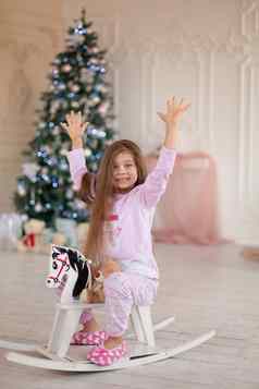 美丽的女孩粉红色的睡衣喜乐木摇摆马礼物圣诞老人圣诞节