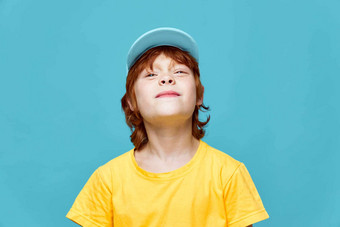 红色头发的人男孩头提高了微笑蓝色的帽黄色的t恤