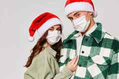 年轻的夫妇穿医疗面具圣诞节帽子假期特写镜头