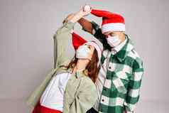 年轻的夫妇脸面具圣诞老人帽子有趣的假期圣诞节夏娃