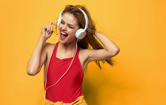快乐的女人耳机红色的t恤黄色的背景音乐