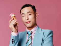 朝鲜文男人。西装持有冰奶油锥粉红色的背景