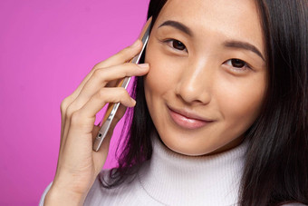 女人亚洲外观会说话的电话特写镜头工作室粉红色的背景微笑