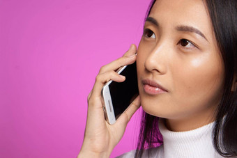 亚洲女人会说话的电话裁剪视图粉红色的背景