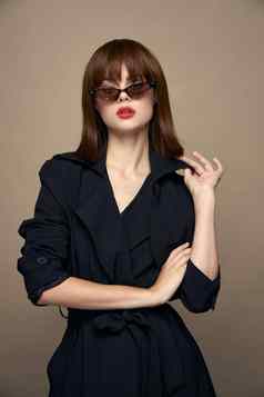 时尚的女人太阳镜米色背景黑色的外套